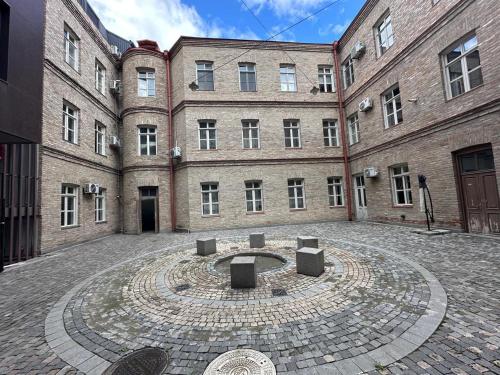 un gran edificio de ladrillo con un patio delante de él en orbeliani cozy flat, en Tiflis