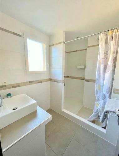 une salle de bain blanche avec un lavabo et une douche dans l'établissement un gout de paradis, à Zonza