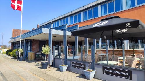 a restaurant with an umbrella in front of a building at Banegaardshotellet in Vojens
