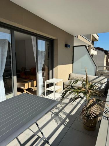 un patio avec un canapé et une plante sur un balcon dans l'établissement La Datcha - New T3 with balcony & parking near train station, à Aix-les-Bains