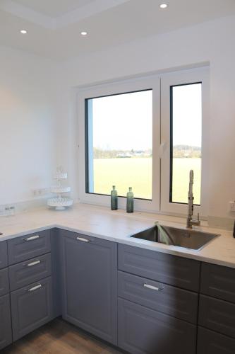 eine Küche mit Spüle und zwei Fenstern in der Unterkunft Emily Apartments, moderne ruhige Wohnung, nur 4 km von der A2 in Leopoldshöhe