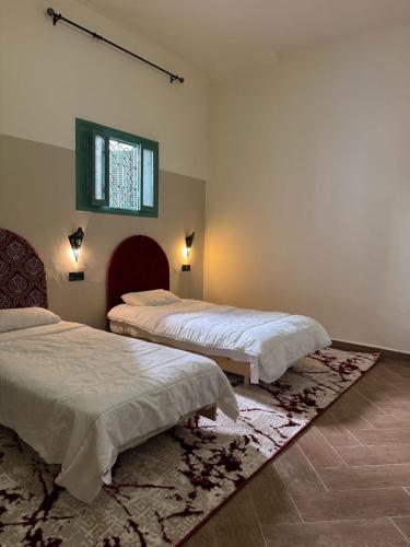 a bedroom with two beds and a window and a rug at Big Apartment in Central Medina 3BR ,view and Jacuzzi Tetouan in Tetouan