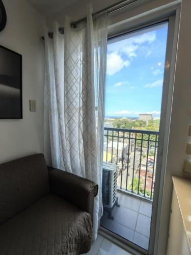 a living room with a couch and a large window at 2-Bedroom Cityscape Residences Bacolod 1001 in Bacolod