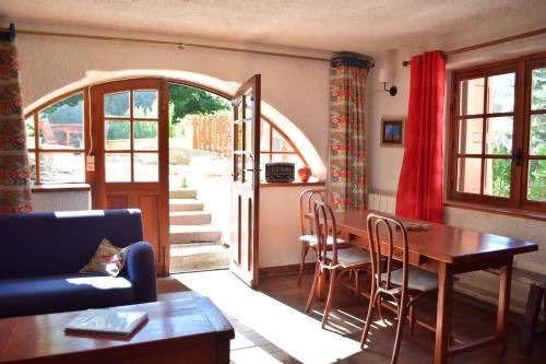 - un salon avec une table, des chaises et une porte ouverte dans l'établissement Appartement chaleureux pour 6 avec jardin et canal, à Briançon