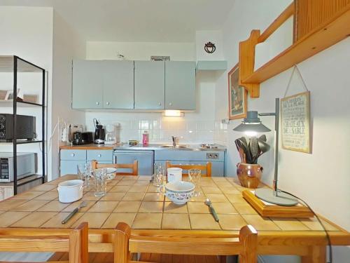 - une cuisine avec une table en bois et des verres dans l'établissement Studio cosy avec jardinet à 300m de la plage - 4 couchages - FR-1-224B-689, à La Guérinière