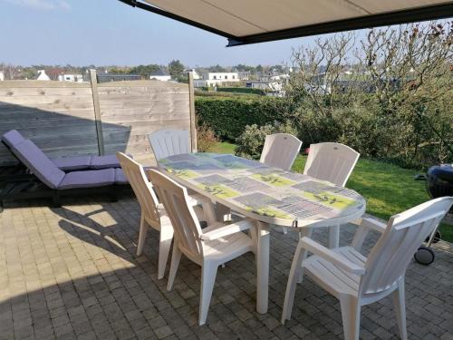 une table blanche et des chaises sur une terrasse dans l'établissement L'horizon, à Plurien