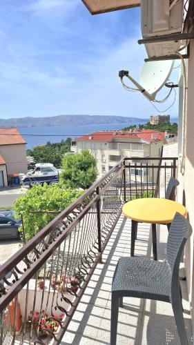 a balcony with a yellow table and chairs and a view at Guesthouse Martina in Senj
