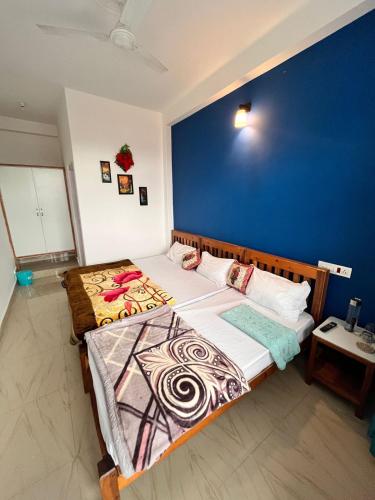 a bedroom with two beds and a blue wall at Bir-Aadri Homestay in Bīr