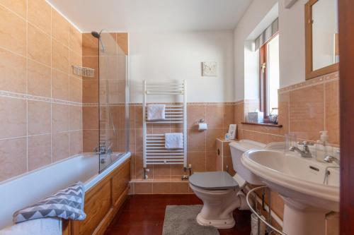 a bathroom with a tub and a toilet and a sink at Wheel Cottage, Landrake in Saltash