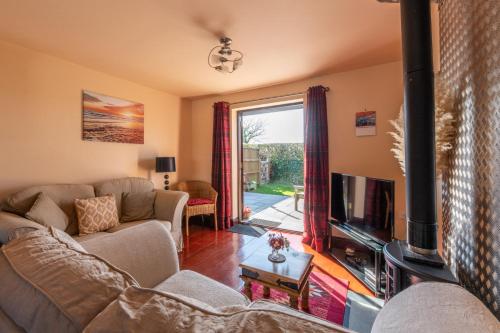 a living room with a couch and a tv at Wheel Cottage, Landrake in Saltash