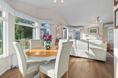 a dining room with a table and white chairs at Kingfisher Lodge in Stratford upon Avon in Alveston