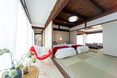 四日市市にあるMiraie Yokkaichi Heizuchoのベッドルーム1室(ベッド2台、赤い椅子付)