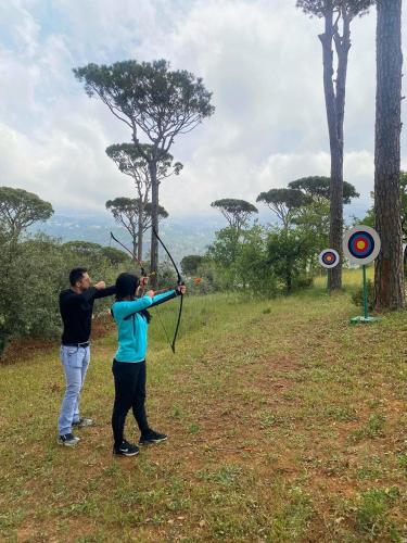a man and a woman holding a bow and arrow at Pineland Hotel and Health Resort in Ḩammānā