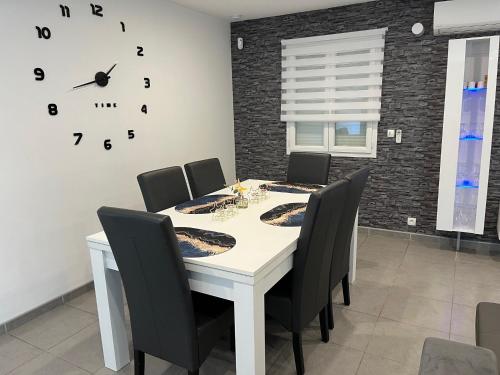 une table à manger avec des chaises et une horloge murale dans l'établissement Villa privative 3 chambres et piscine priv près Carcassonne, à Carcassonne