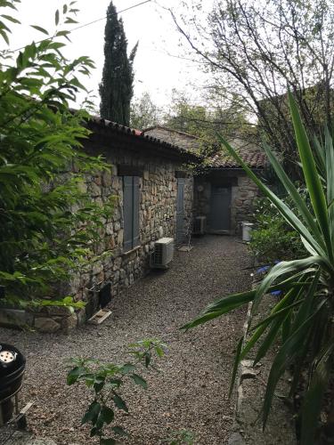 une maison en pierre avec une cour à côté d'un bâtiment dans l'établissement Charmante maison, à Fayence