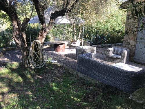 une terrasse avec des chaises et une balançoire sous un arbre dans l'établissement Charmante maison, à Fayence