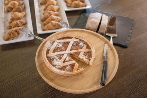 a pie on a wooden plate on a table with other pastries at Hotel ANDER in Brunico