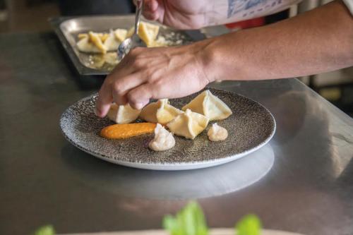 a person holding a plate of food on a table at Hotel ANDER in Brunico