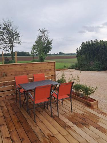 une table et quatre chaises sur une terrasse en bois dans l'établissement les deux tilleuls, à Les Rosiers
