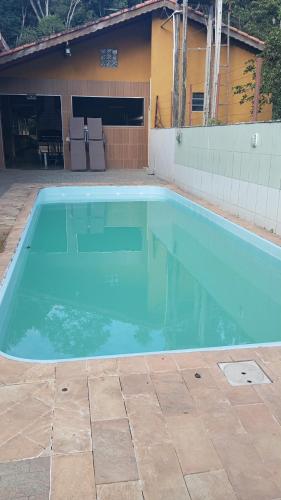a swimming pool with blue water in front of a house at CHÁCARA recanto das nuvens 2 in Arujá