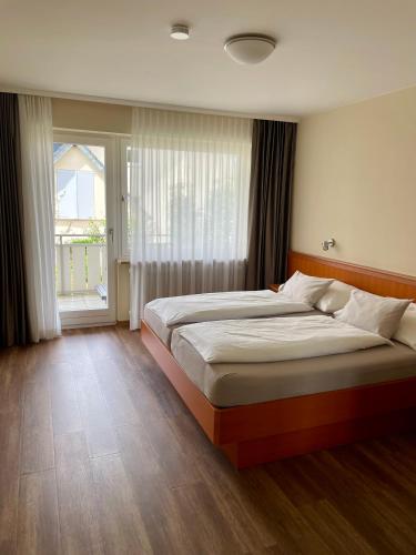 a bedroom with two beds and a large window at Hotel Gästehaus Zürn in Wasserburg