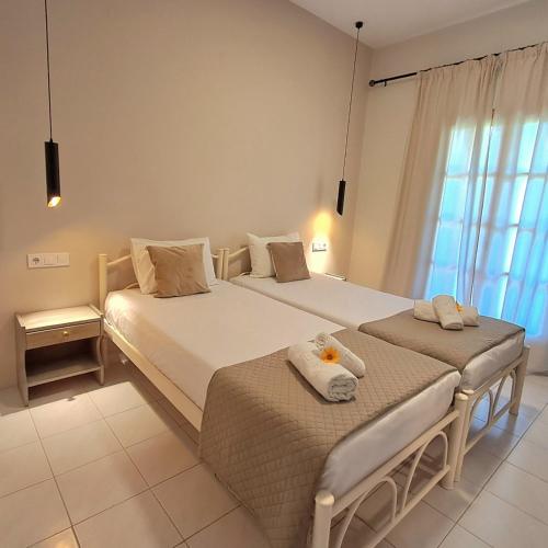 a bedroom with two beds and a window at Olga's Garden Apartments in Almiros Beach