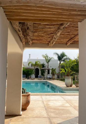 a pool in a house with a wooden roof at Palais Bleu Nomade Essaouira in Aït Imouni