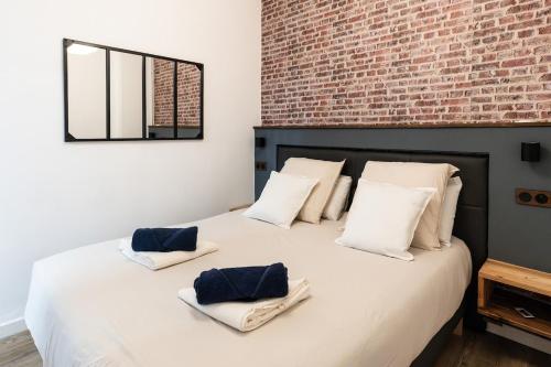 une chambre avec un grand lit blanc avec un mur de briques dans l'établissement L'atelier caché, à Toulouse