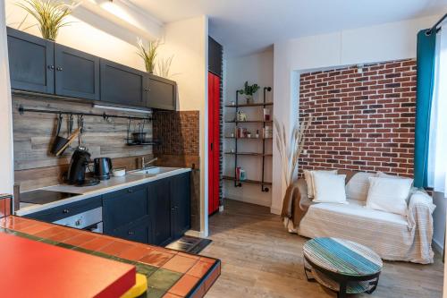 une cuisine avec un canapé et un mur en briques dans l'établissement L'atelier caché, à Toulouse