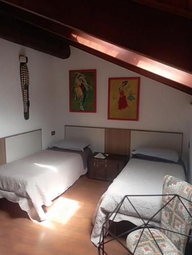 a bedroom with two beds and a chair in it at Monferrato Inn in Rivarone