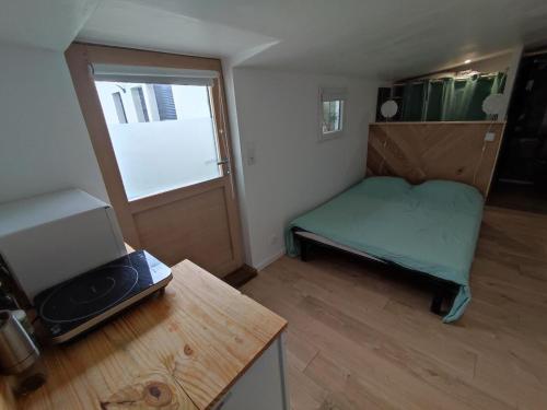 Cette petite chambre comprend un lit vert et une fenêtre. dans l'établissement Studio Rezé, à La Celle-sous-Gouzon