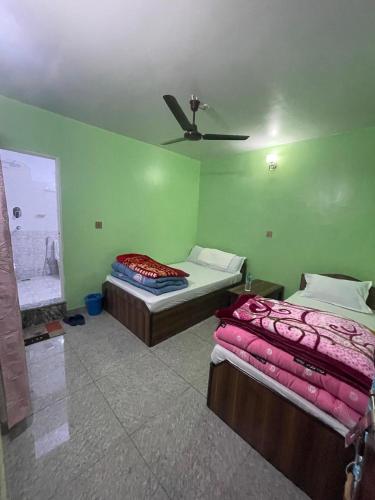 two beds in a room with green walls at INT Airport Thakali Bhansa Ghar and Lodge in Pokhara