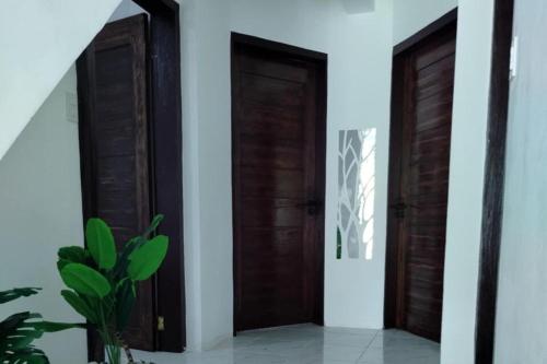 zwei Holztüren in einem Raum mit einer Pflanze in der Unterkunft Marias couple room in Puerto Galera