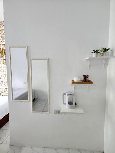 two mirrors on a white wall with a coffee maker at Marias couple room in Puerto Galera