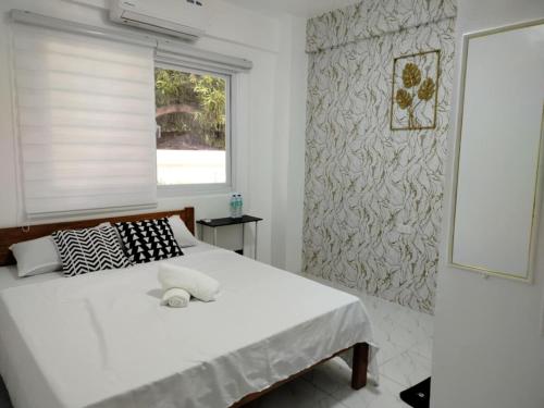 a bedroom with a white bed and a window at Marias couple room in Puerto Galera