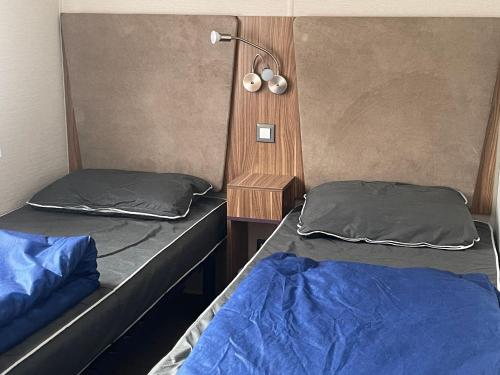 - 2 lits dans une chambre avec une lampe sur le mur dans l'établissement Pleasant Mobile Home Ba680 - Siblu Bonne Anse La Palmyre, aux Mathes