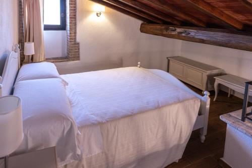 a bedroom with a white bed and a window at Borgo Il Poggiaccio Residenza d'Epoca in Sovicille