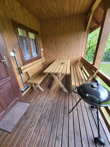 a porch of a cabin with a bench and a door at Domki Sami Swoi maly domek in Susiec