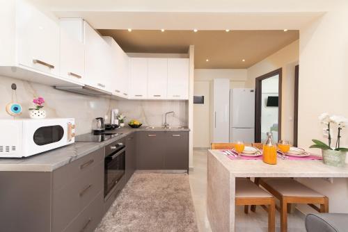 a kitchen with white cabinets and a table with a microwave at Modern Colorful House 2 rhodos in Rhodes Town