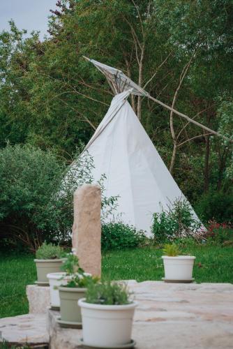 un tipi blanc dans un jardin avec des plantes en pot dans l'établissement Tipi / Nature / Détente, à Bragny-sur-Saône