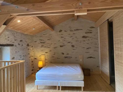 1 dormitorio con 1 cama blanca en una pared de piedra en Gîte Le COCON au Clarou, en Valleraugue