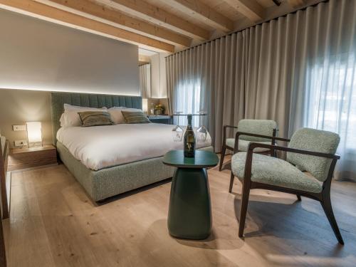 a bedroom with a bed and a chair and a table at Agriturismo Prà dell'Ort - Wishing Wellness in Valdobbiadene