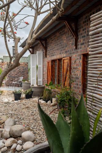 a brick house with a yard with rocks and plants at Yzerfontein 3 Bed House with Pool & Sea Views in Yzerfontein
