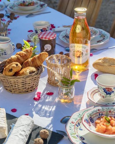 une table avec de la nourriture, une corbeille de pain et une bouteille dans l'établissement La Cour Souveraine -Chambre d'hôtes, La Sablonneuse, à Mosles