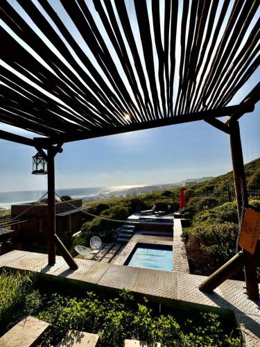 a view of a swimming pool under a wooden umbrella at Yzerfontein 3 Bed House with Pool & Sea Views in Yzerfontein