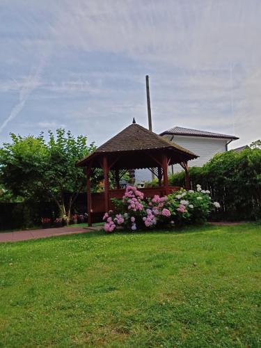a wooden gazebo with flowers in a yard at Dom Gościnny Sówka in Pobierowo