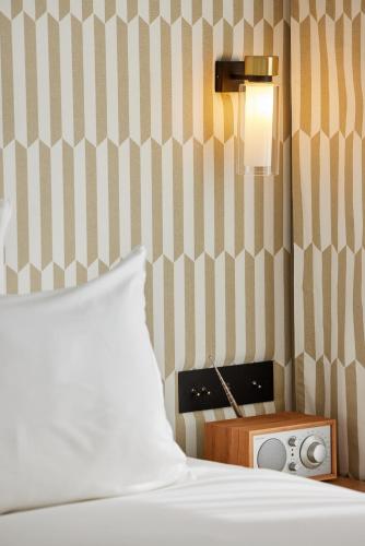 a bedroom with a bed and a night stand with a radio at Hôtel Noucha in Paris