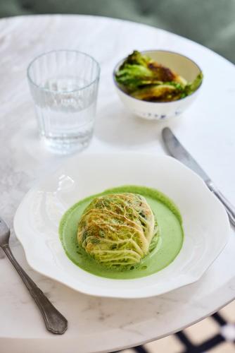 a table with a plate of food and a bowl of broccoli at Hôtel Noucha in Paris