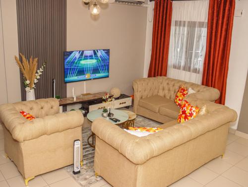 Una sala de estar con dos sofás y un televisor. en MAXIM HOUSE, Denver, 24h sur 24 Internet, Electricité, Eau, Canal Sat, Parking Privé, Sécurité,Gardien, en Douala