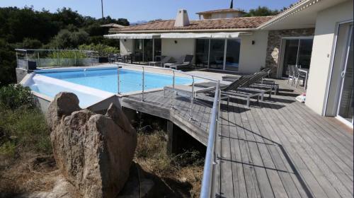 a house with a swimming pool and a wooden deck at Padulaccia by Pinarello Villa Services in Pinarellu